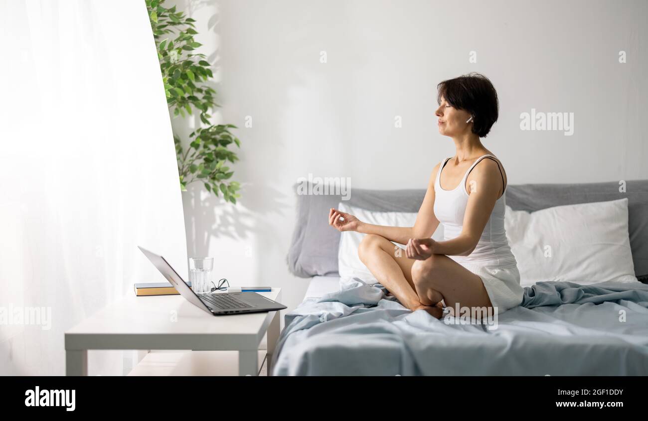 Woman meditating on bed Stock Photo
