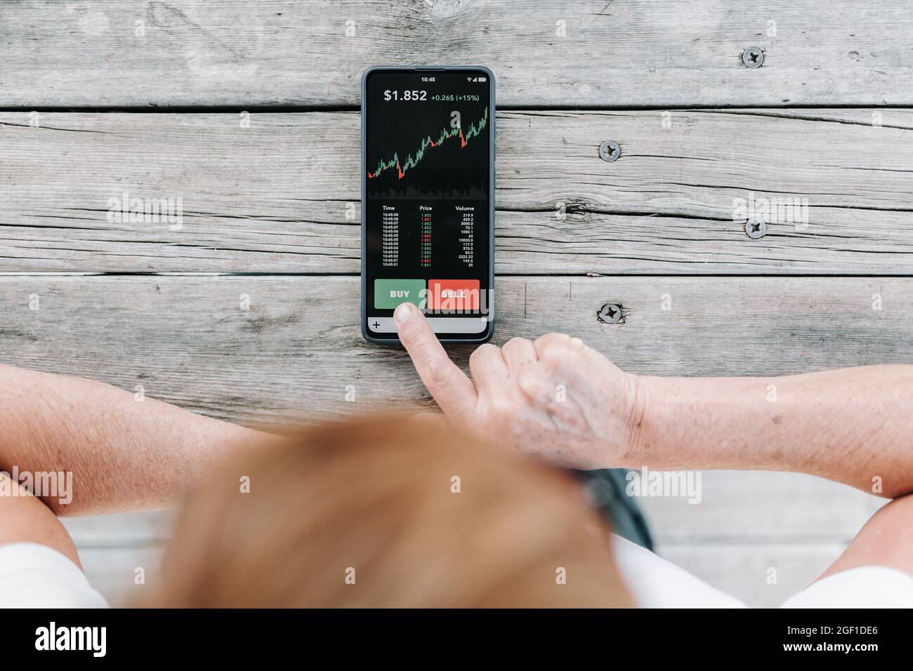 Investor woman using investment mobile phone app to buy crypto currencies Stock Photo