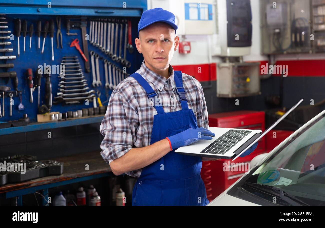 Mechanic man using laptop checking car in workshop Stock Photo