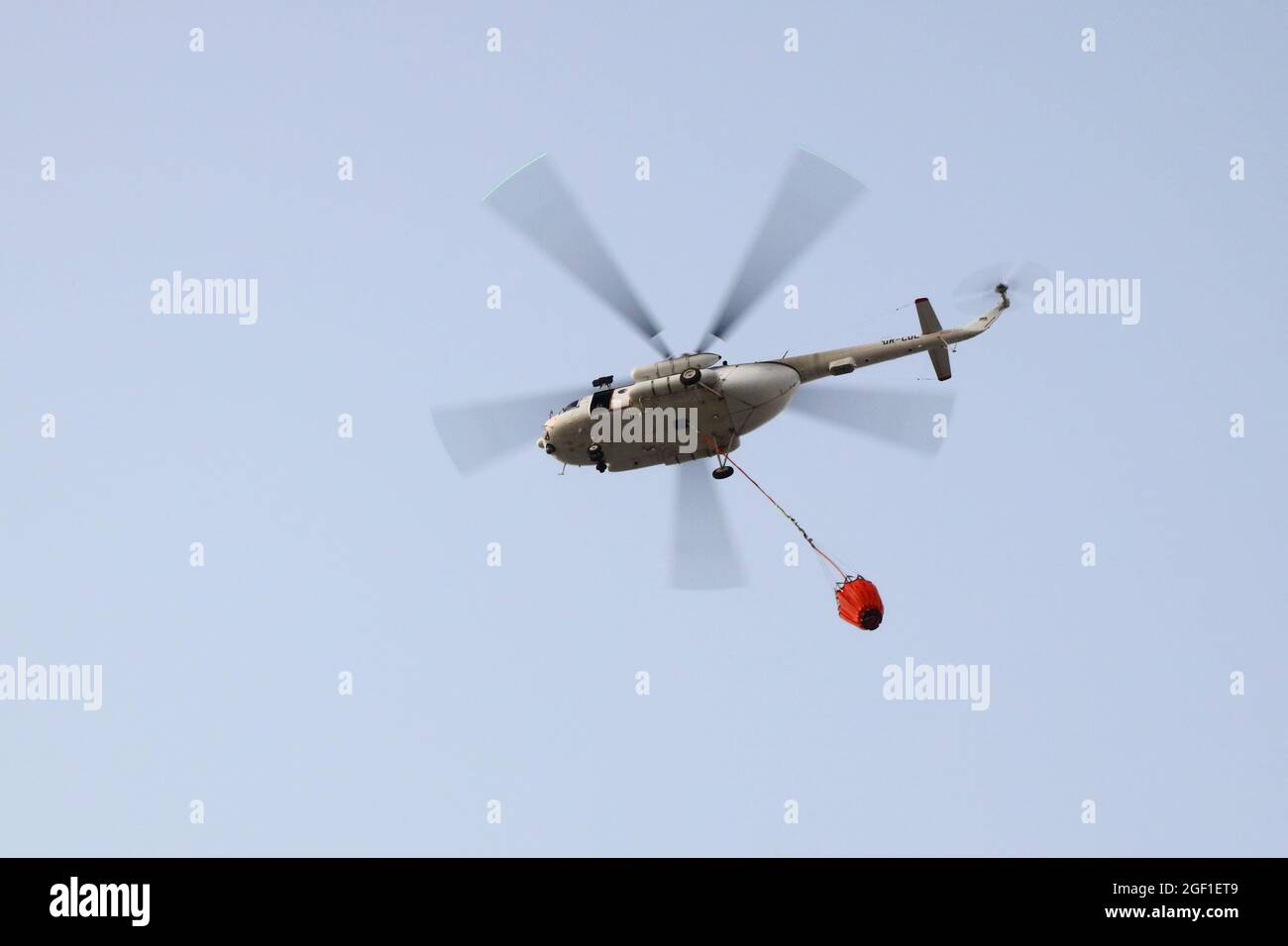 Fire fighting helicopter with water bucket on the background of a gloomy  sky Stock Photo - Alamy