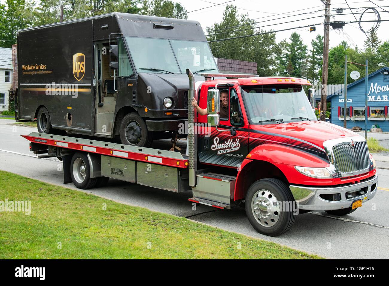 A broken down UPS truck loaded onto a roll back wrecker In Speculator, NY USA Stock Photo