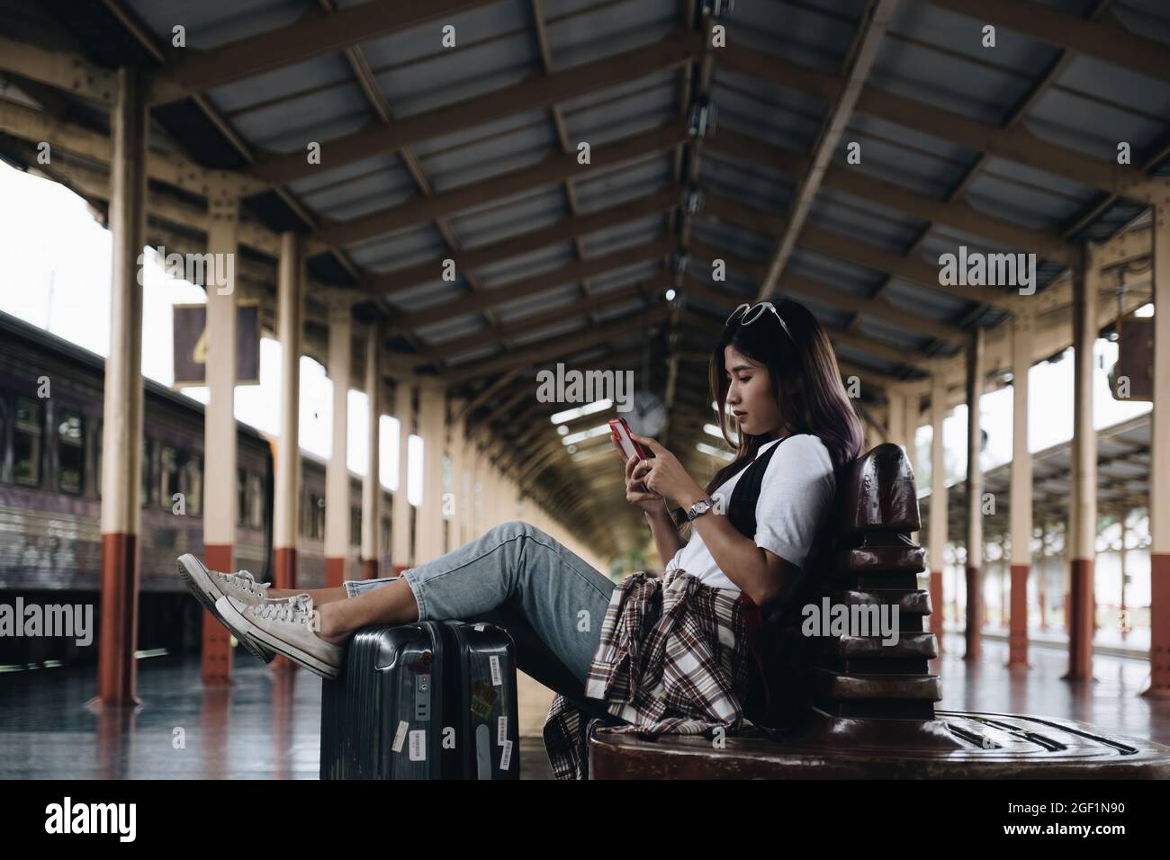 Image of A traveler checking message from her friend and waiting at train station. Travel concept Stock Photo