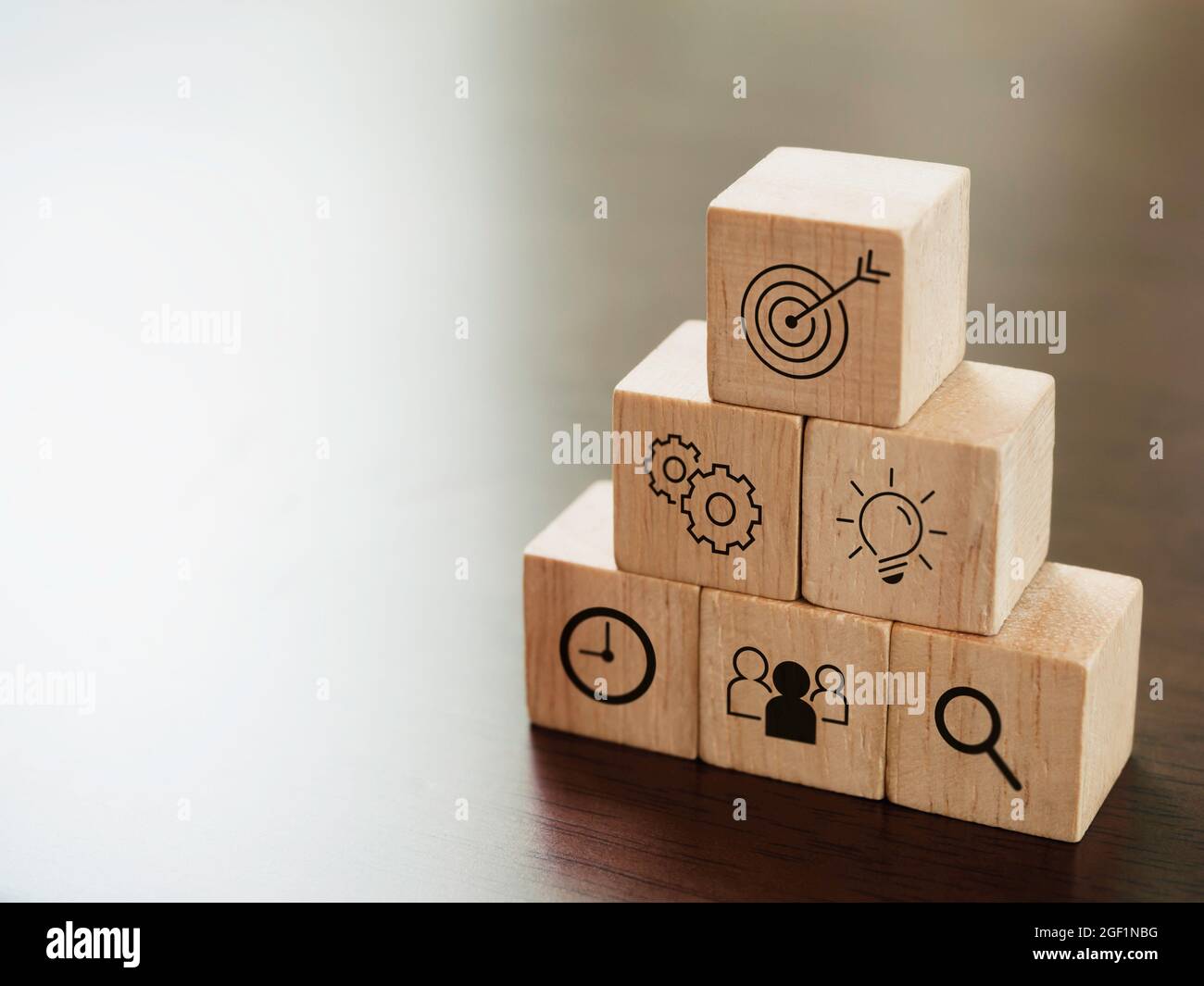 Modern business icons on wooden cube blocks, pyramid steps on desk with ...