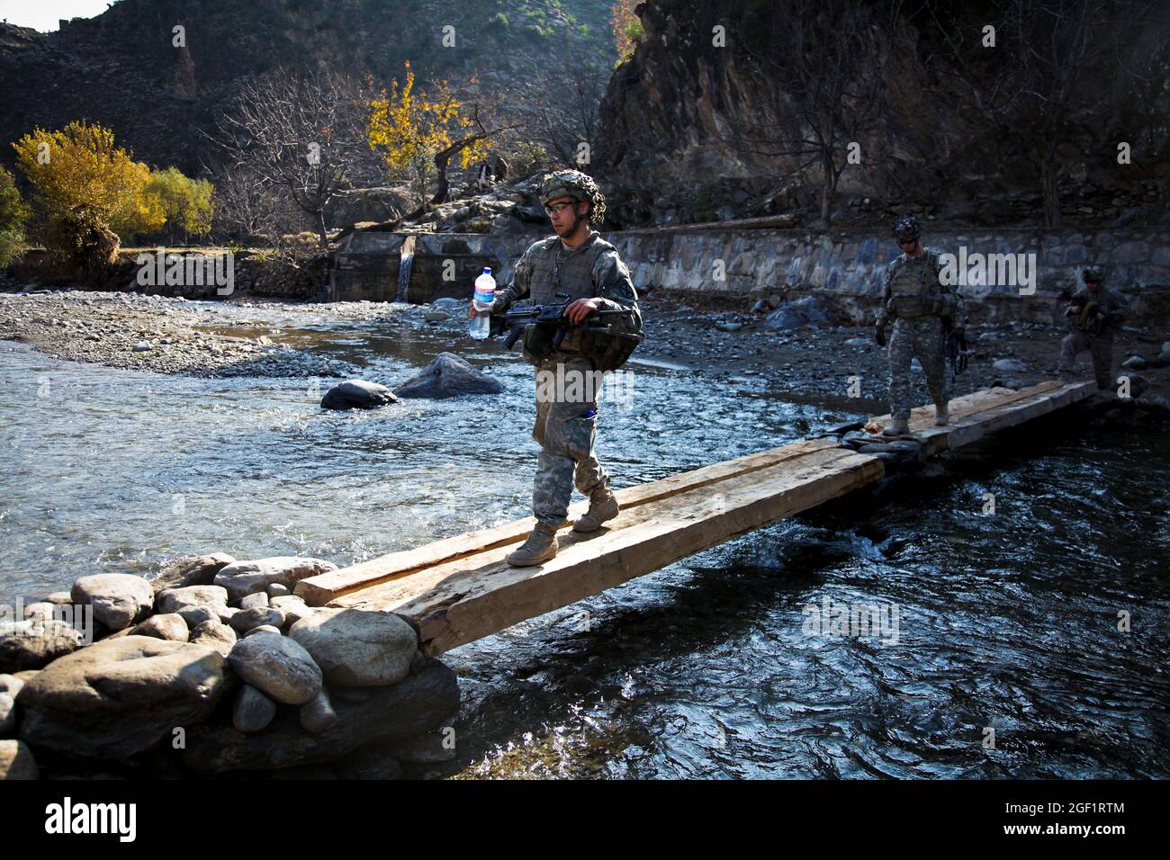 U.S. Army Pfc. Emeterio Jimenez and fellow Soldiers assigned to Combat Company, 1st Battalion, 32nd Infantry Regiment, 3rd Brigade Combat Team, 10th Mountain Division, cross a river as they approach the village of Lachey in the Shigal district of Kunar province, Afghanistan on Dec. 7. Stock Photo