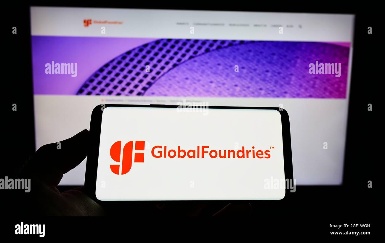 Person holding cellphone with logo of US semiconductor company GlobalFoundries Inc. (GF) on screen in front of webpage. Focus on phone display. Stock Photo