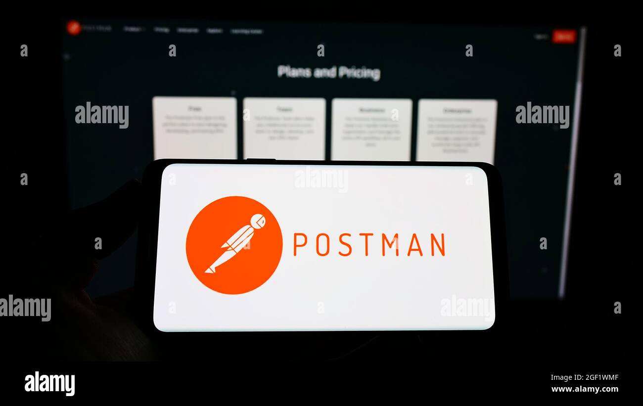 Person holding cellphone with logo of US collaboration platform company Postman Inc. on screen in front of business webpage. Focus on phone display. Stock Photo