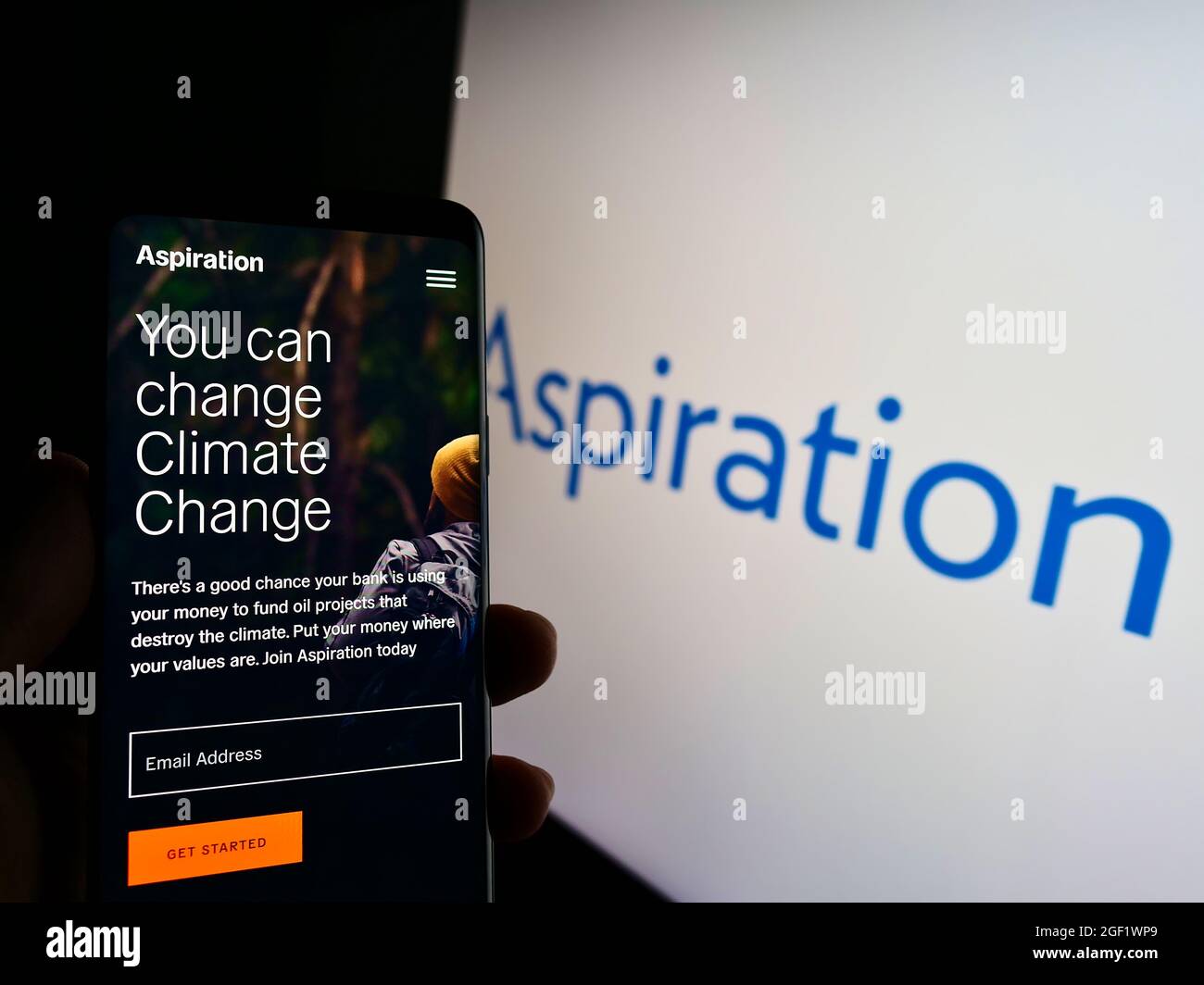 Person holding smartphone with website of US fintech company Aspiration Partners Inc. on screen in front of logo. Focus on center of phone display. Stock Photo