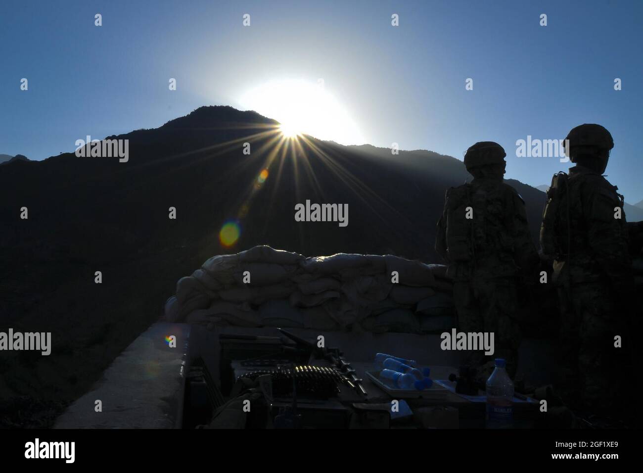 Soldiers assigned to Company B, 2nd Battalion, 27th Infantry Regiment, Task Force No Fear, 3rd Brigade Combat Team, 25th Infantry Division, TF Bronco, pull guard duty as the sun rises over Observation Post Coleman outside of Combat Outpost Monti in eastern Afghanistan's Kunar Province May 5. OP Coleman is situated at the mouth of the Pech River Valley and the Kunar River Valley, which is some of the most dangerous terrain in Afghanistan. Stock Photo