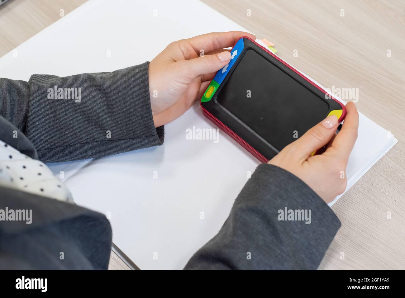 The woman is holding a reading device for the visually impaired