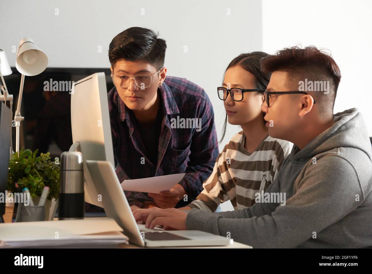 Serious university students in glasses testing new program they were working on and looking at computer screen Stock Photo