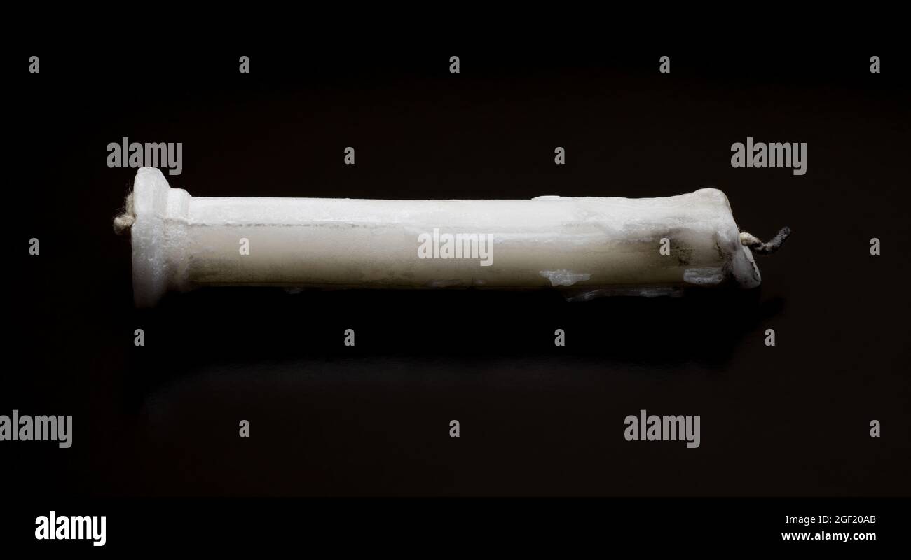 Old burnt out a dusty candle on isolated dark background Stock Photo