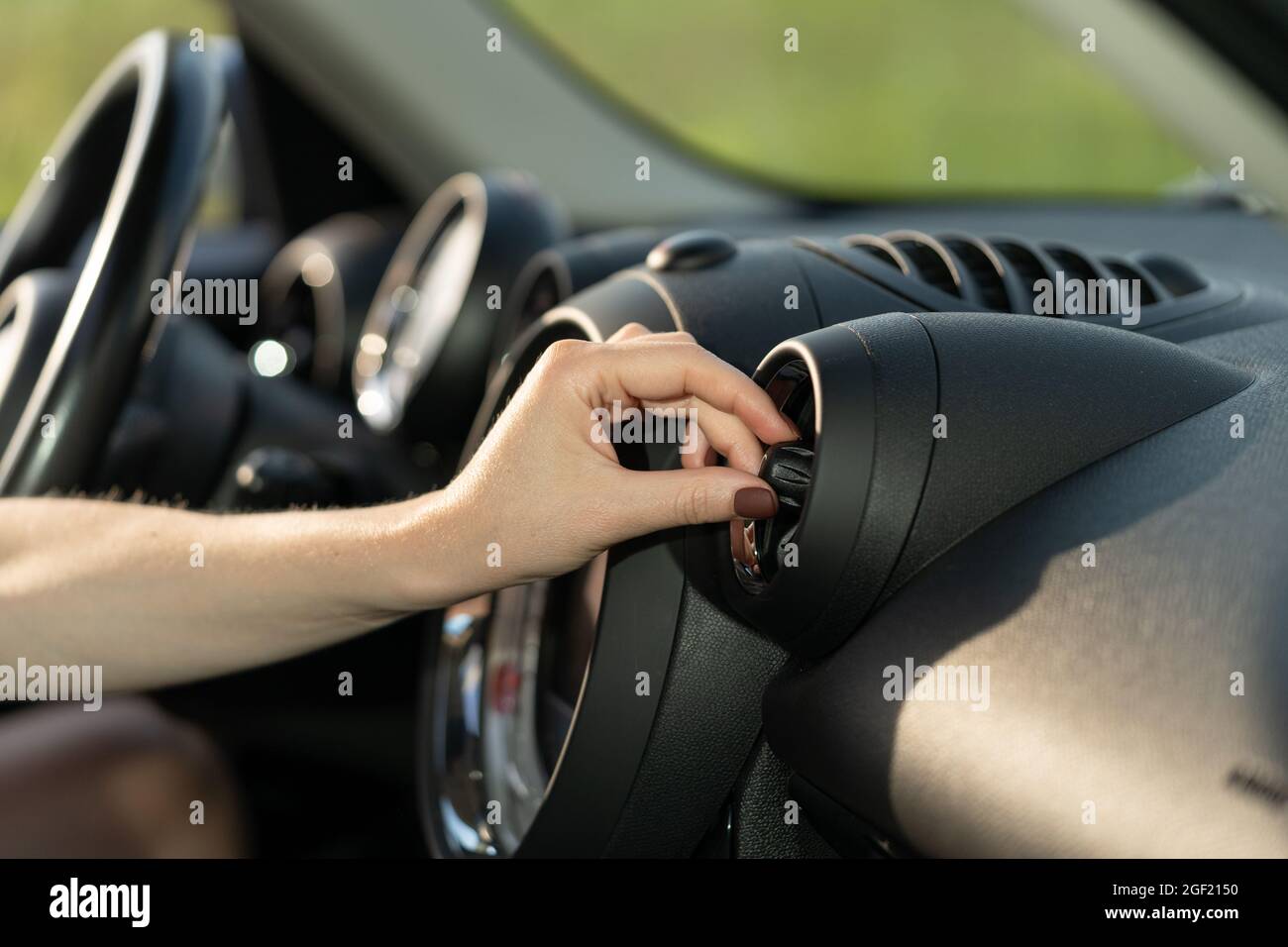 Woman turn on air conditioner in car at vehicle panel grid cooling