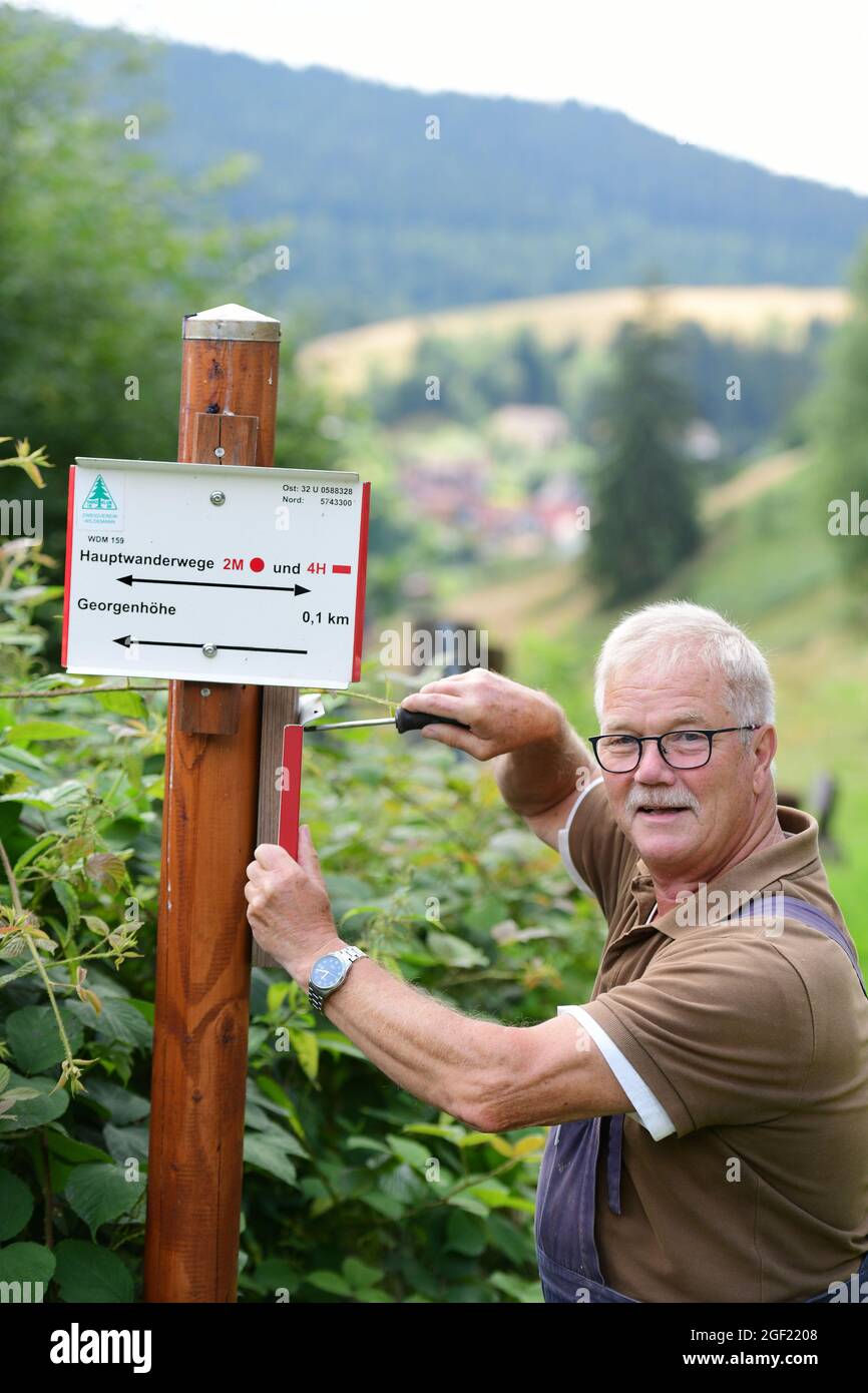 Wildemann, Germany. 04th Aug, 2021. Klaus Petersen, the main trail warden of the Harzklub e.V., screws on a signpost for a hiking trail in the Harz Mountains. Hiking in the Harz would certainly only be half as nice if there wasn't an extensive network of trails, signposting in the right place and good hiking maps! To ensure this, many volunteer members of the Harzklub are in action every day. Credit: Frank May/dpa/Alamy Live News Stock Photo
