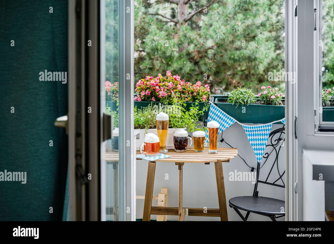 Wooden table with beer glasses on green balcony Stock Photo