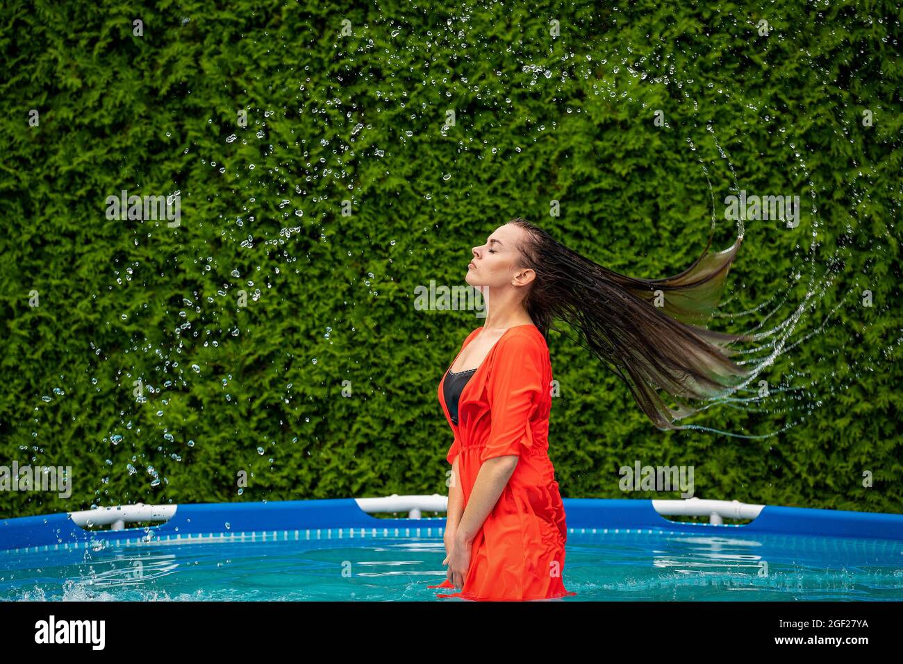Long-haired girl with wet hair throws her head back Stock Photo