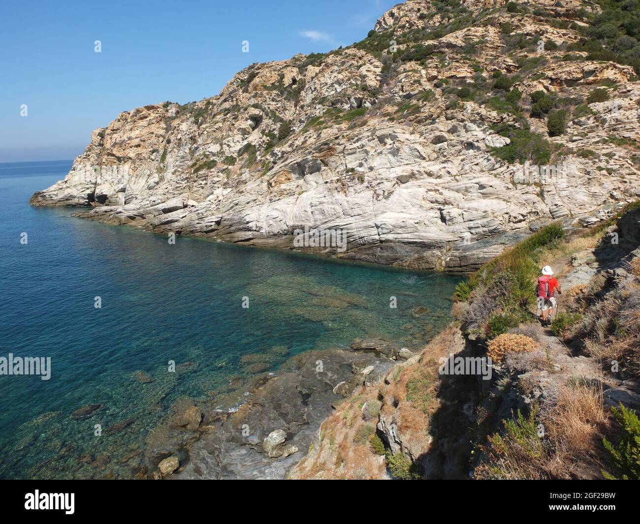 Man walking on the rocky coast of Cap Corse, Sentier du Douanier near Port de Centuri, northeast Corsica, France Stock Photo