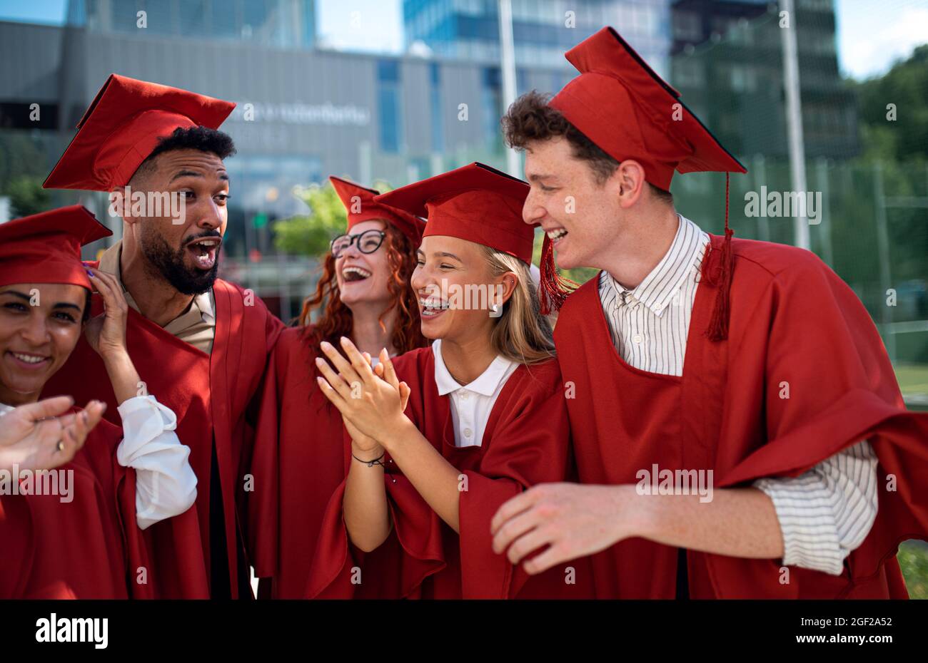 Group of cheerful university students celebrating outdoors, graduation concept. Stock Photo