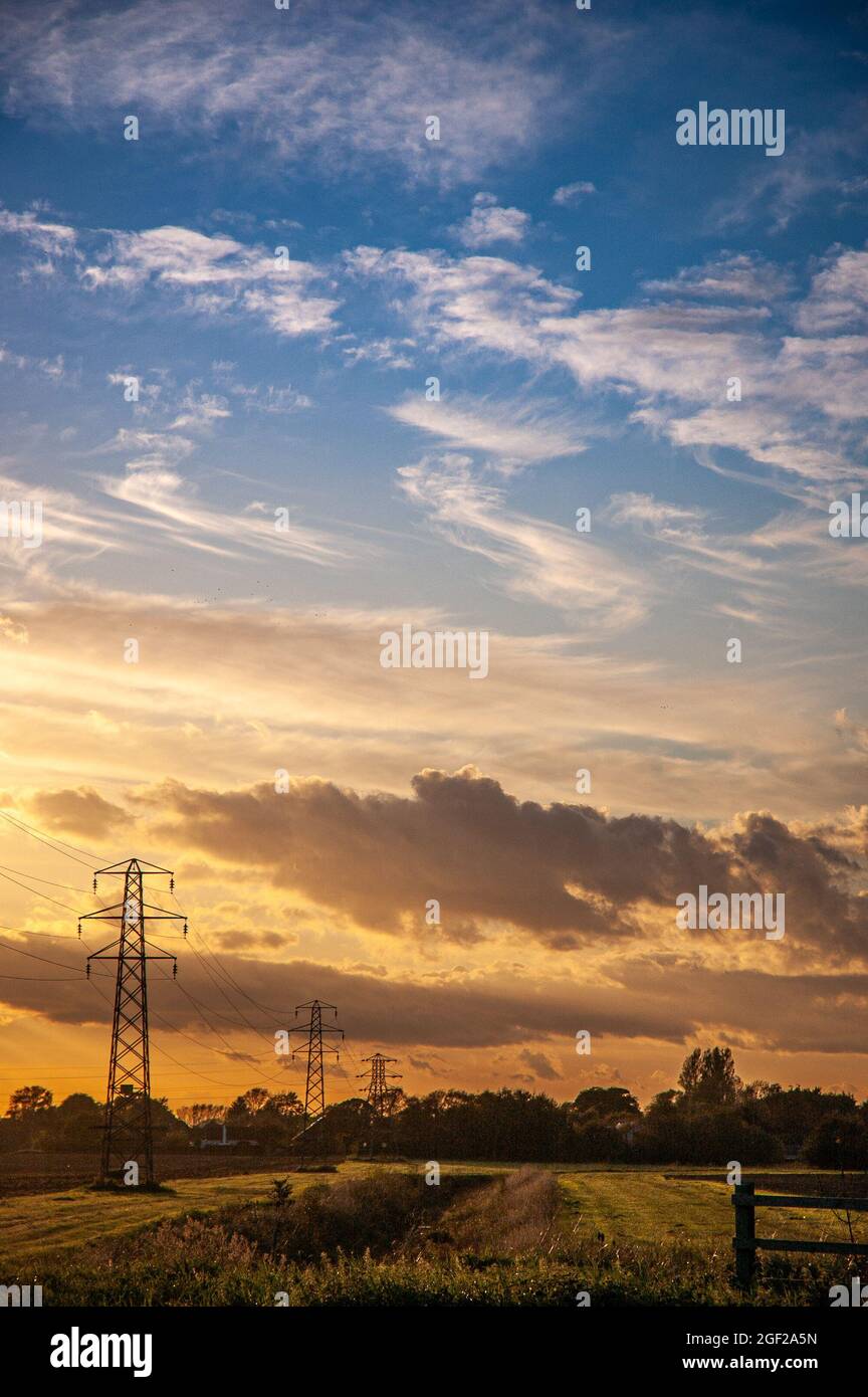 Electricity pylons, power lines and trees against a cloudy sky at ...