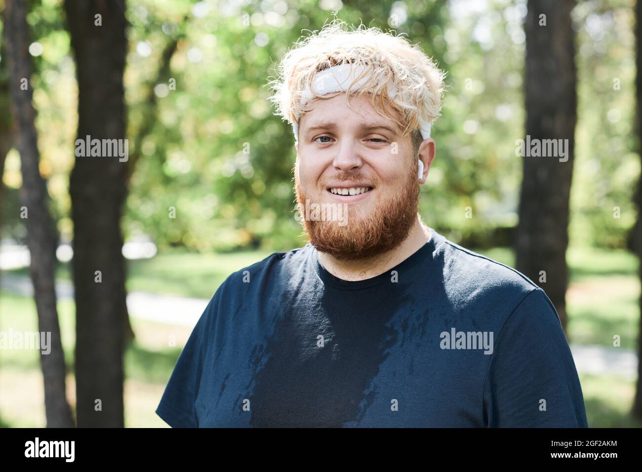 Portrait of overweight bearded man smiling at camera while training in the park Stock Photo