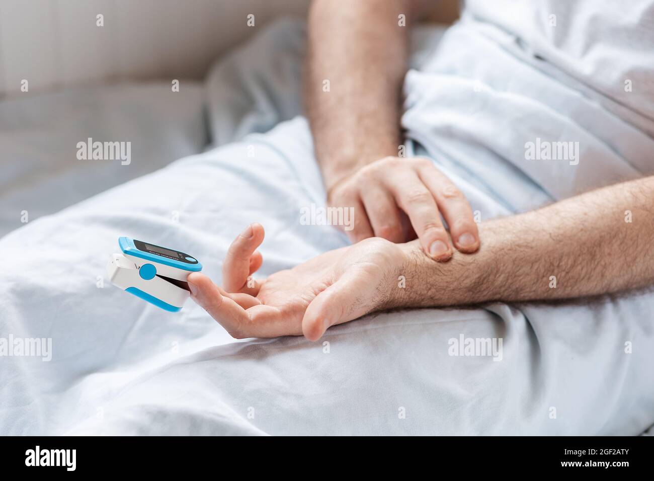 Patient lying at bed with pulse oximeter adnd try to measure the pulse