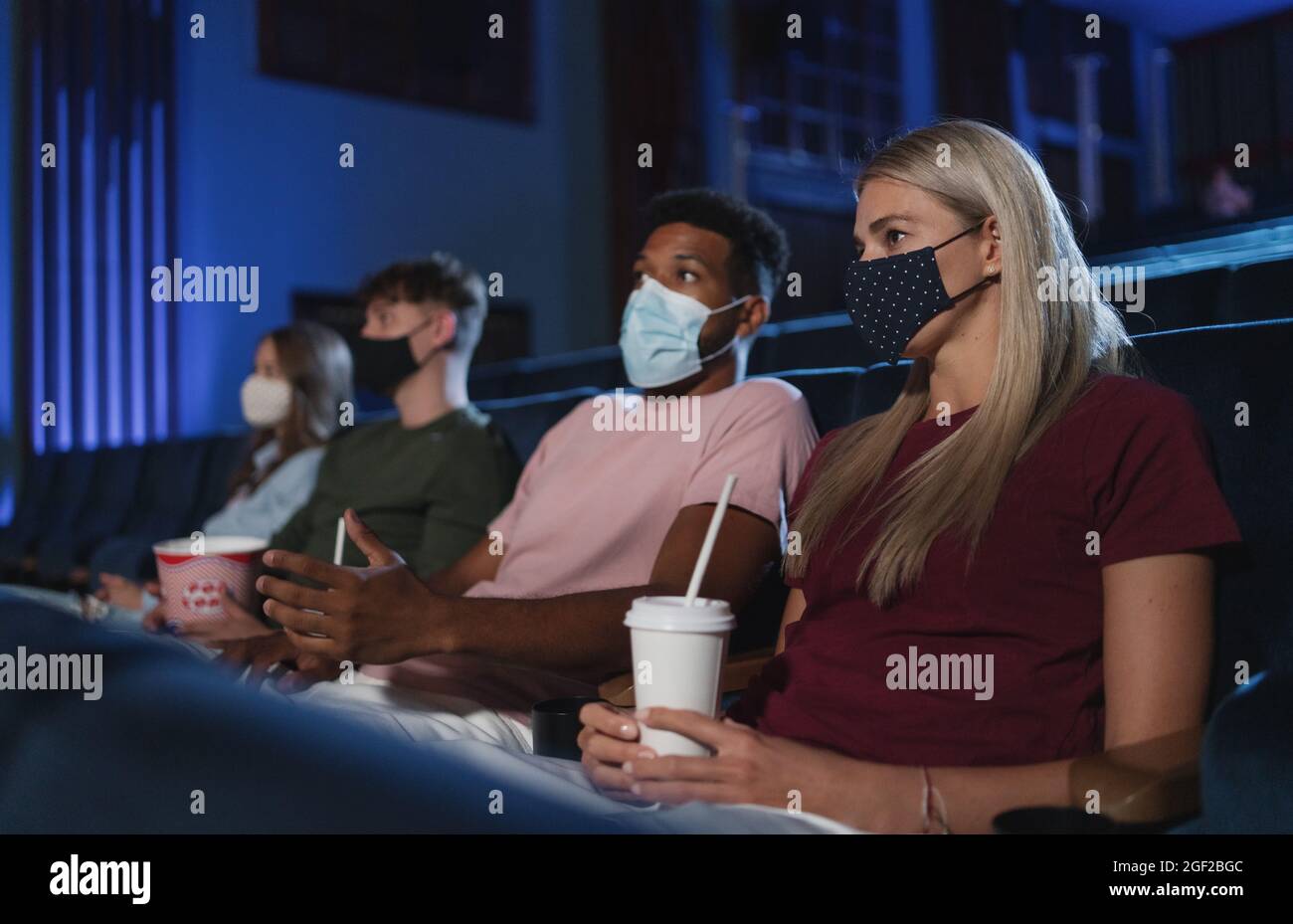 Young people watching film in the cinema, coronavirus concept. Stock Photo