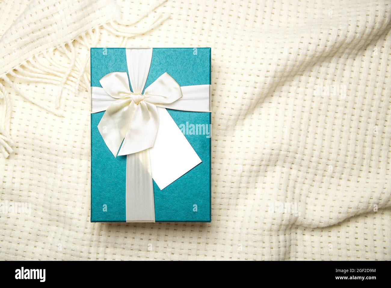 Gift box with empty white blank gift tag mock up. Christmas, birthday or wedding gift. Stock Photo