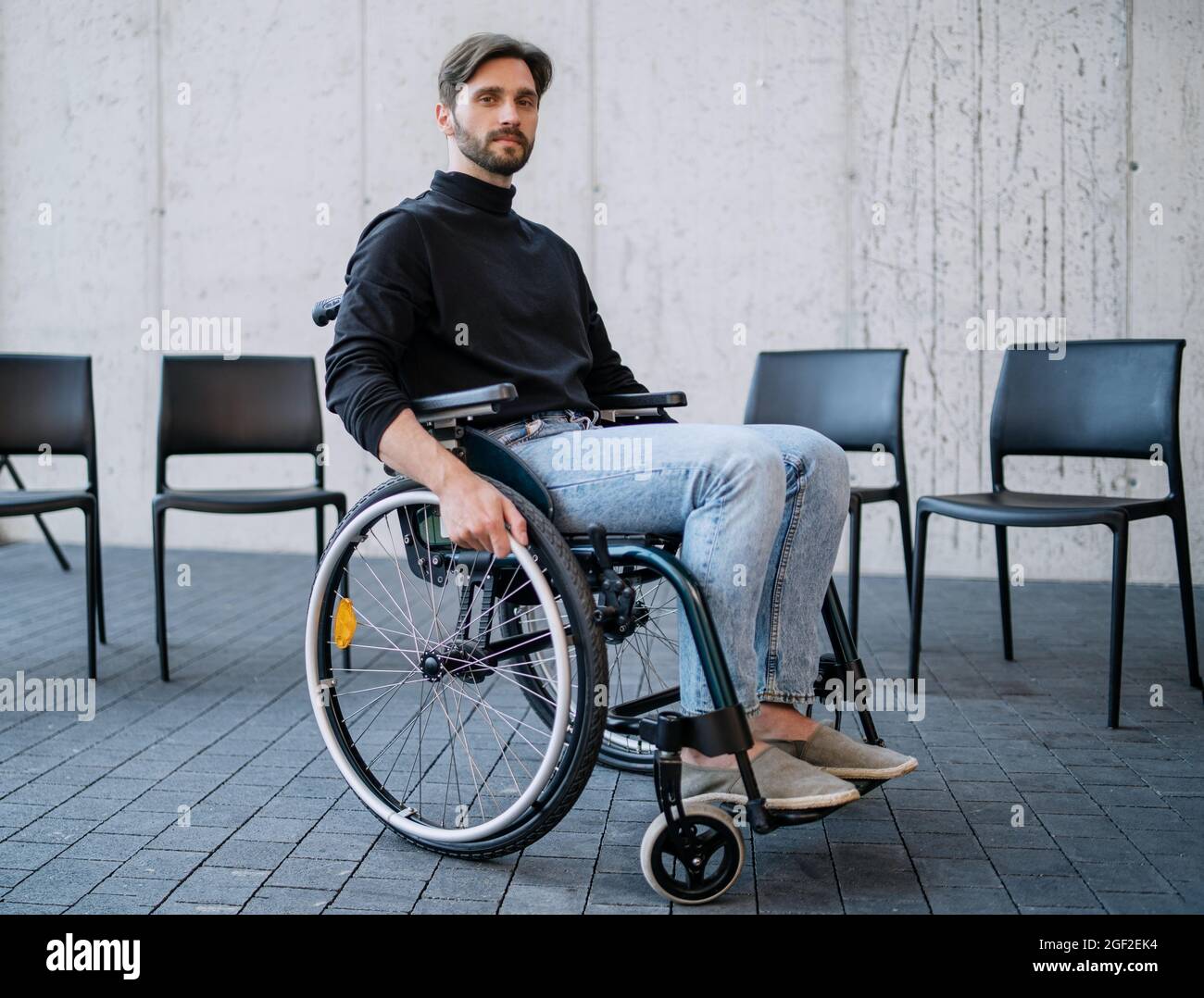 Portrait of sad man in wheelchair on group therapy, looking at camera. Stock Photo