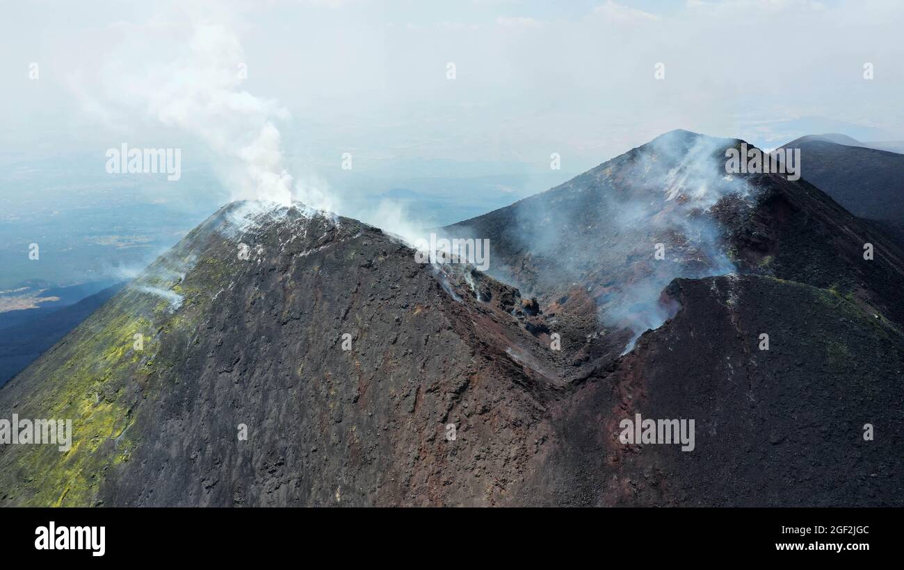 Crater Etna top view from above in a panoramic aerial photo with sulphure and smoke at degassation. Stock Photo