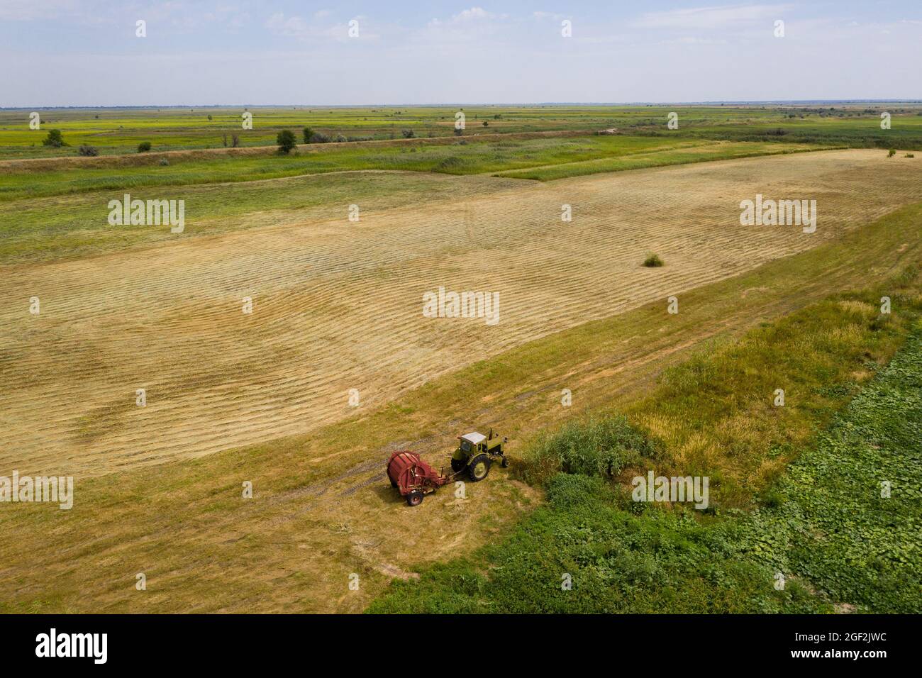 Tractor for making straw bales on harvested wheat field. Aerial view Stock Photo
