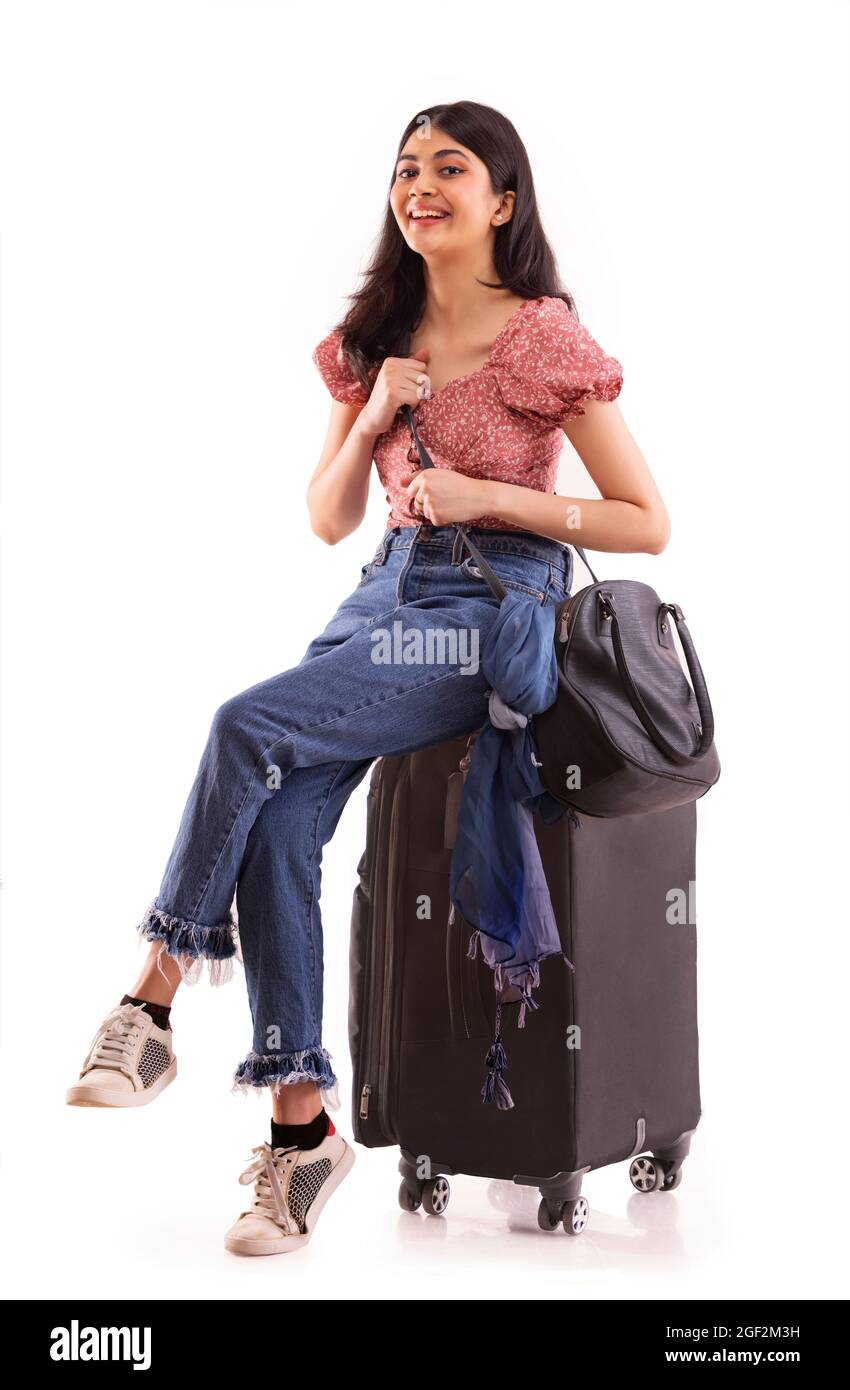 Portrait of a young travelling woman sitting with her luggage. Stock Photo