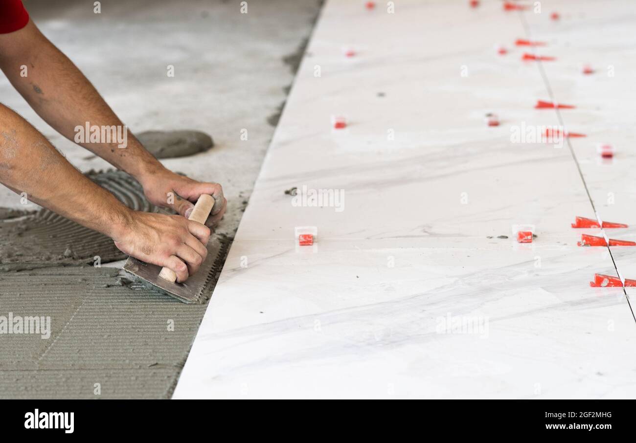 Laying Ceramic Tiles. Troweling mortar onto a concrete floor in