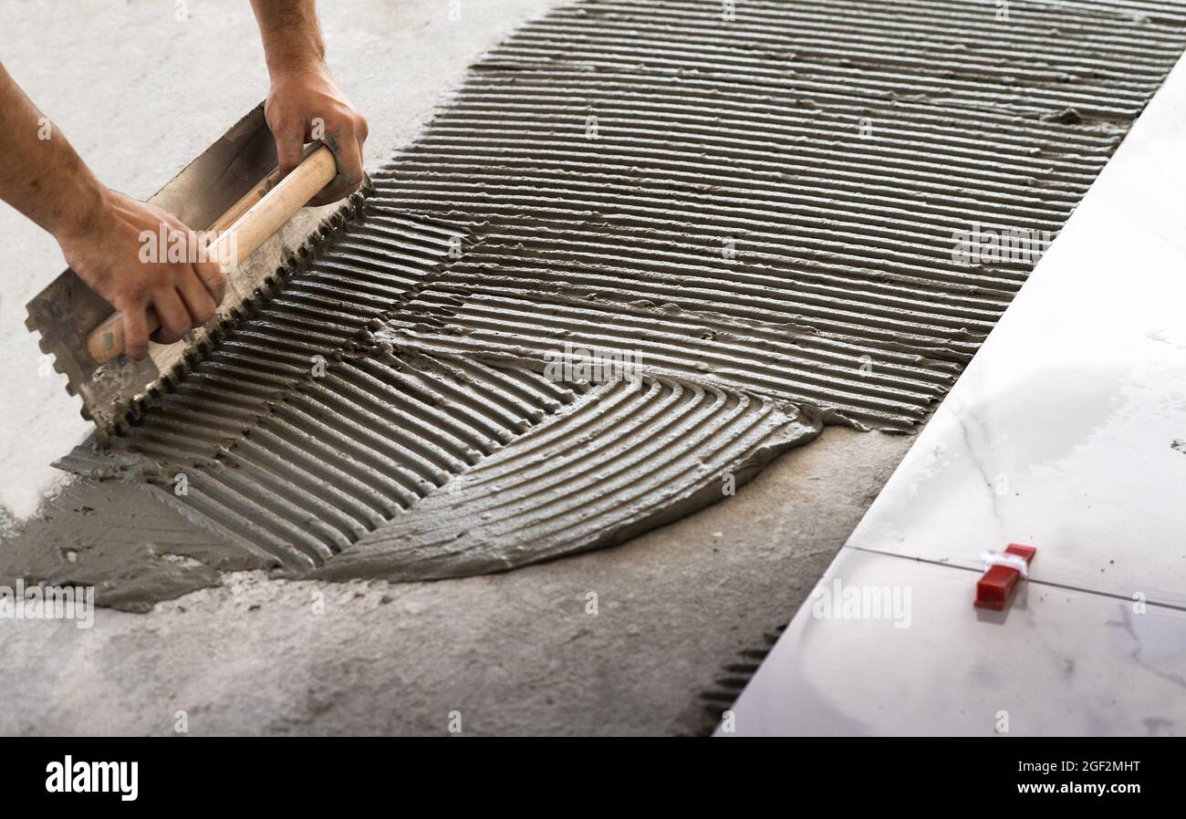 Laying Ceramic Tiles. Troweling mortar onto a concrete floor in