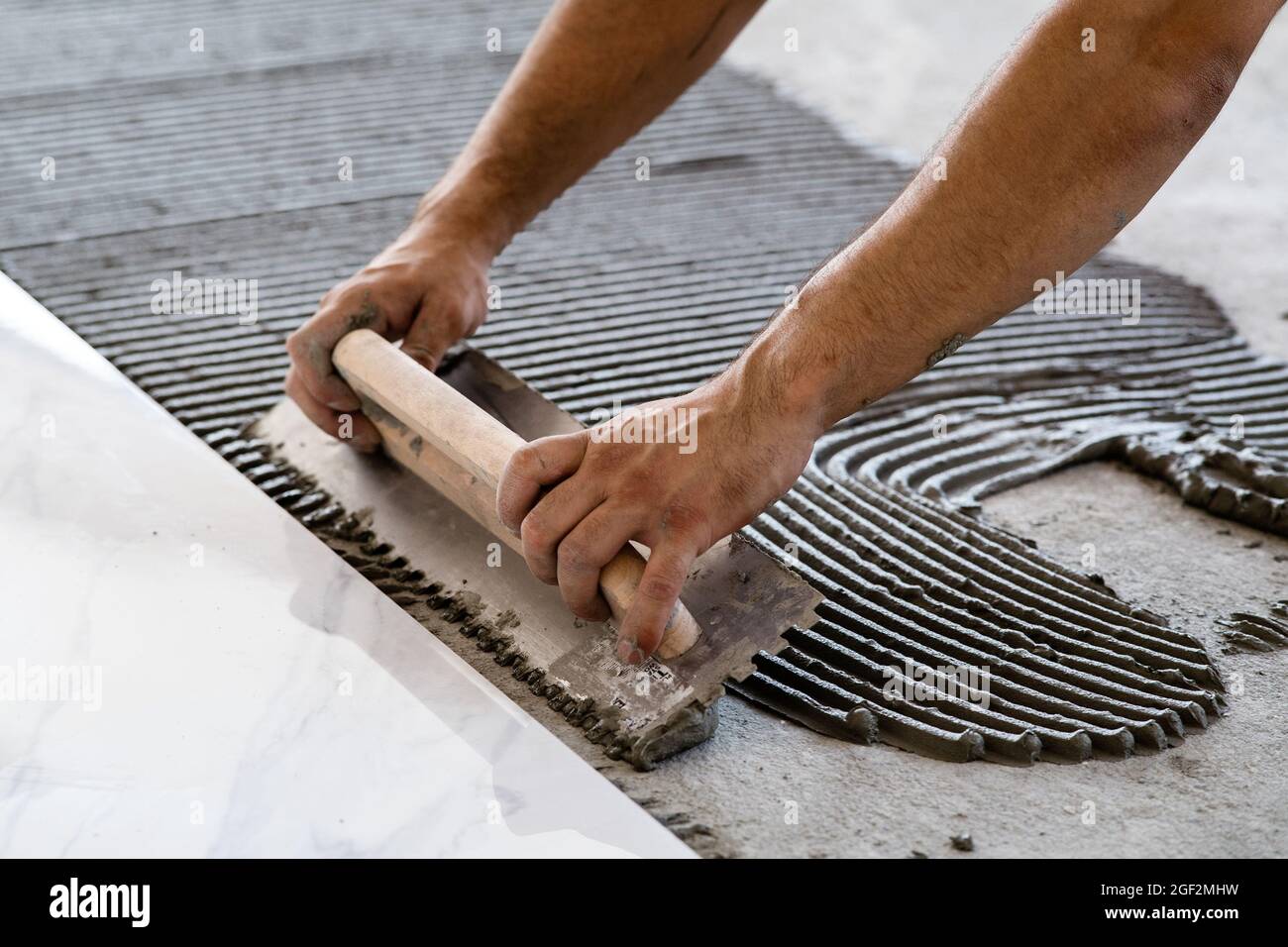 Laying Ceramic Tiles. Troweling mortar onto a concrete floor in