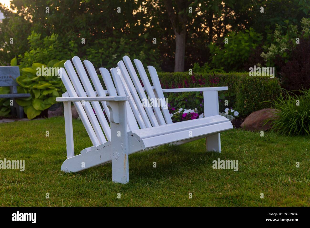 White adirondack double chair overlooking in a garden setting Stock