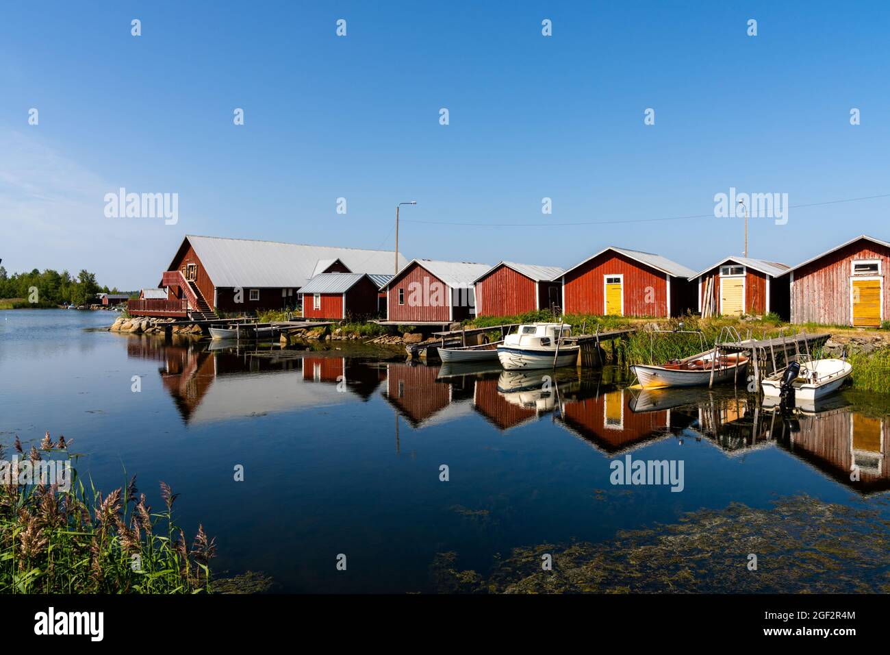 Svedjehamm, Finland - 28 July, 2021: colorful fishing cottages and boats reflected in the water under a blue sky Stock Photo