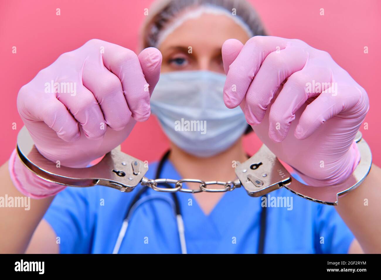 Concept of stay at home. The hands of a medic in protective gloves and medical uniforms are handcuffed, close-up Stock Photo