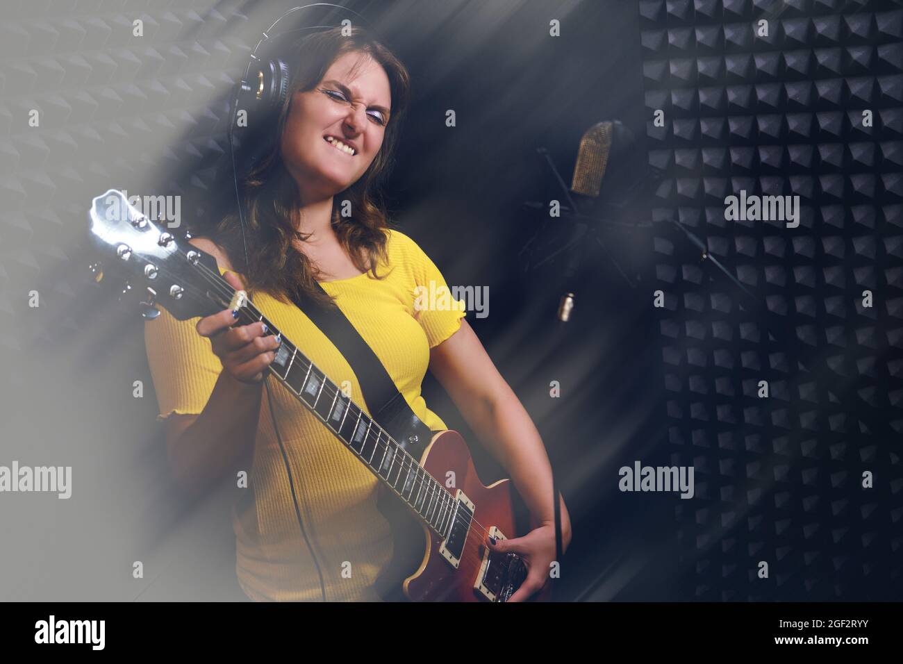 A woman plays music on a red electric guitar. Female guitarist recording a  song at the recording Studio. musician at the counter of a professional mic  Stock Photo - Alamy