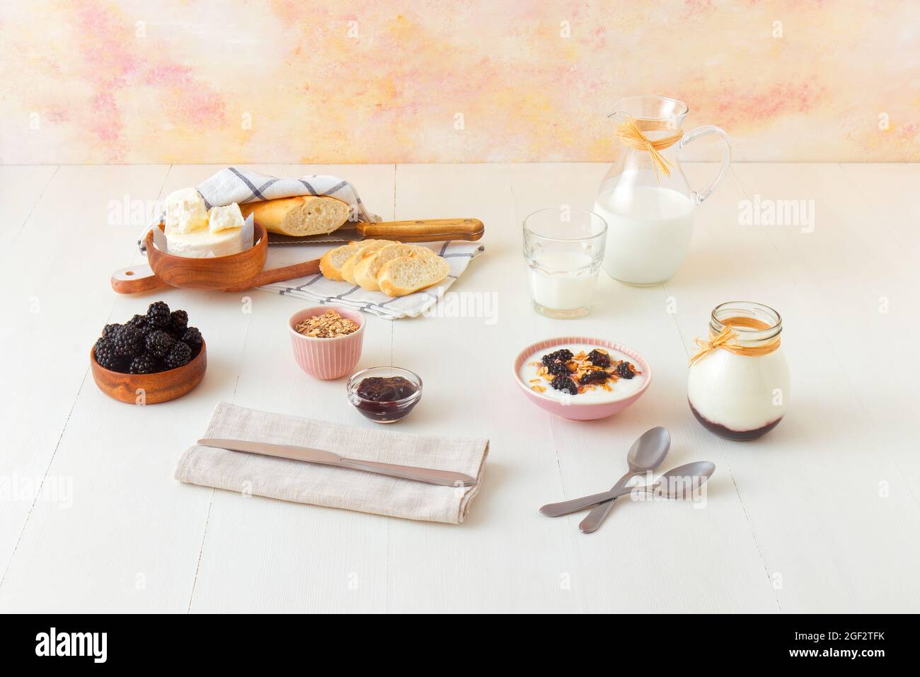 Bowl of blackberries, milk, yoghurt with oatmeals, fresh cheese and bread, a table set for breakfast, ingredients from the local farmers market. High Stock Photo