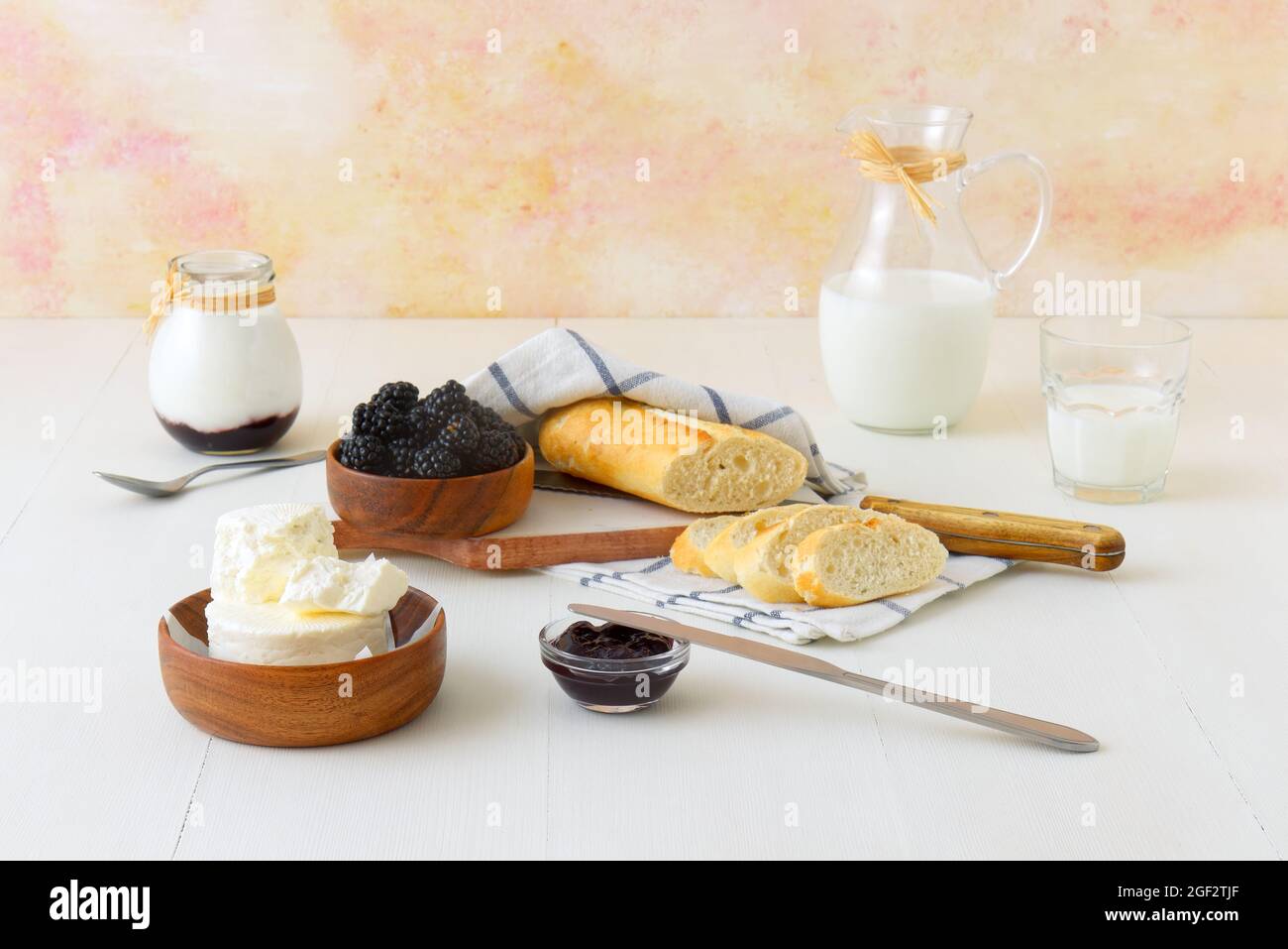 Bowl of blackberries, fresh cheese, milk, yoghurt and bread, a table set for breakfast, ingredients from the local farmers market. Low angle view. Stock Photo