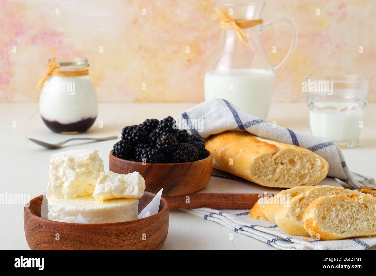 Bowl of blackberries, milk, yoghurt, fresh cheese and bread, a table set for breakfast, ingredients from the local farmers market. Closeup, front view Stock Photo