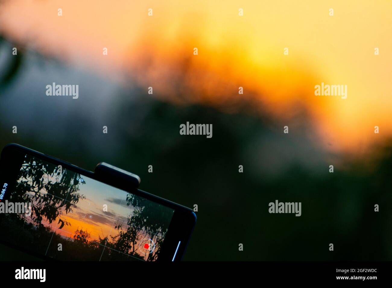 Photograph on a mobile phone while recording a sunset time lapse with a sun over the sky of Madrid, Spain. Europe. Horizontal photography. Stock Photo