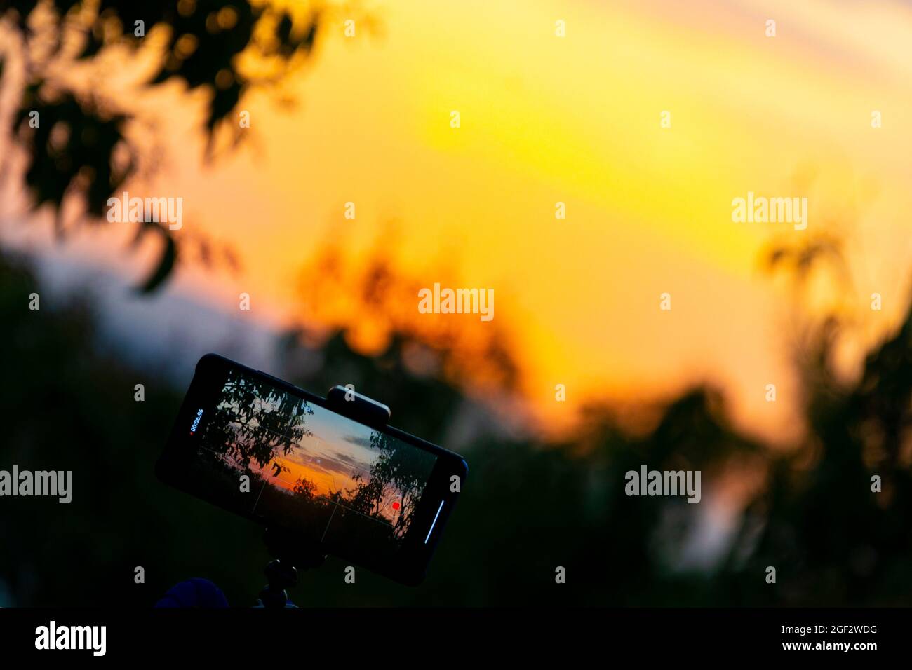 Photograph on a mobile phone while recording a sunset time lapse with a sun over the sky of Madrid, Spain. Europe. Horizontal photography. Stock Photo