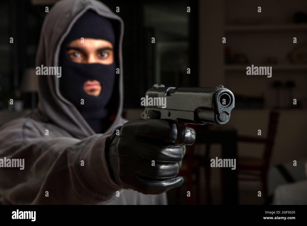Robbery in store. Robber is aiming and threatening with gun in shop. Stock  Photo