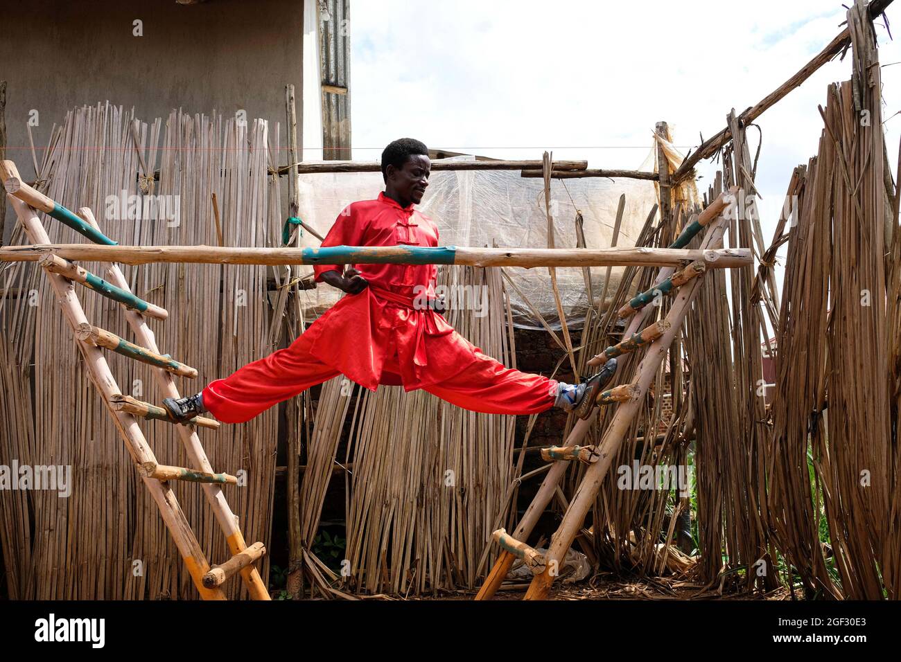 (210823) -- WAKISO, Aug. 23, 2021 (Xinhua) -- Manisuru Ssejjemba stretches during his Chinese martial arts training at a makeshift training center behind his house in Katooke, north of Uganda's capital Kampala, Aug. 17, 2021. Ssejjemba set up a makeshift training center behind his house where he trains youngsters to help promote the Kung Fu culture in Uganda.TO GO WITH 'Ugandan Kung Fu fan passes on skills to youngsters' (Photo by Hajarah Nalwadda/Xinhua) Stock Photo