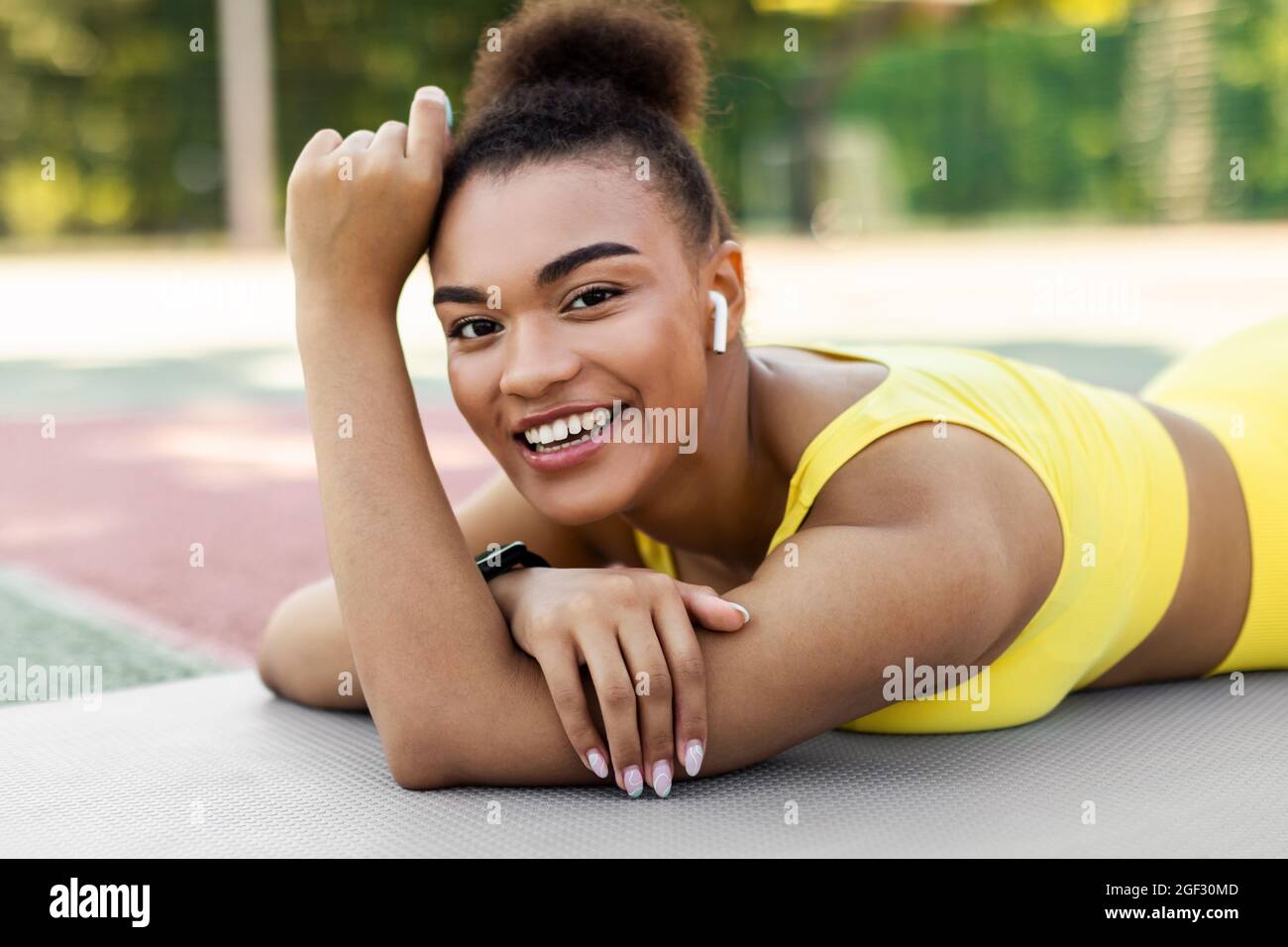 Sporty black woman in yellow sportswear lying and posing Stock Photo ...