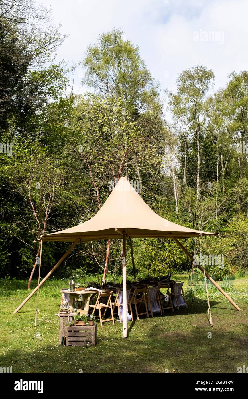 Dining table and chairs under a canopy for a woodland naming ceremony. Stock Photo