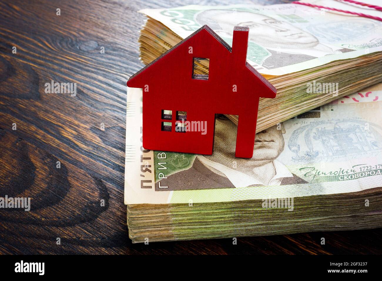 Ukrainian money hryvnia and model of home. Buy property or mortgage in Ukraine. Stock Photo