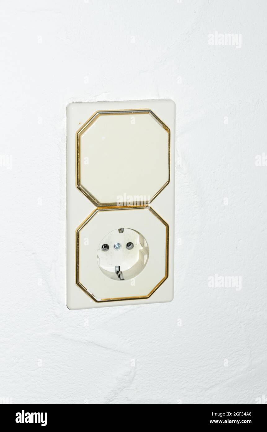 Modern light switch and german power outlet or socket on white wall