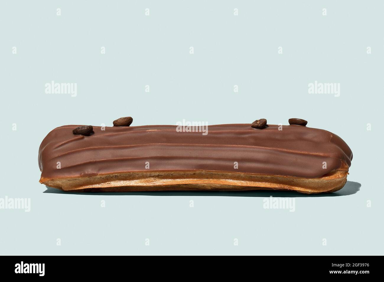 Chocolate eclair with coffee beans on light blue background isolated Stock Photo