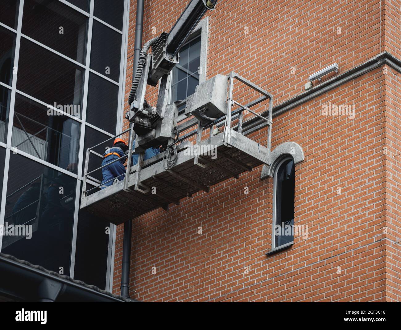 Worker repair facade of the building at height in lifting cradle